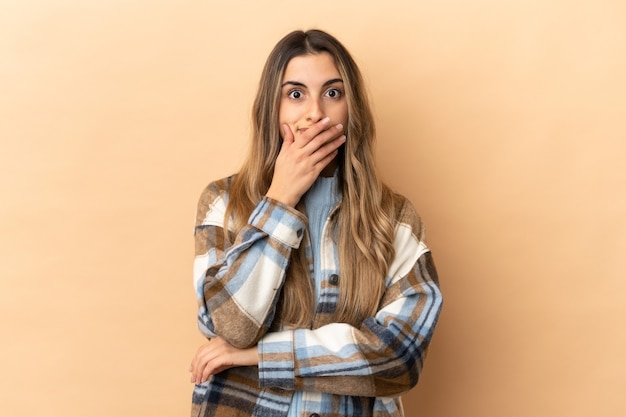 Young caucasian woman isolated on beige background surprised and shocked while looking right