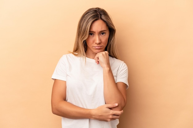 Young caucasian woman isolated on beige background thinking and looking up, being reflective, contemplating, having a fantasy.