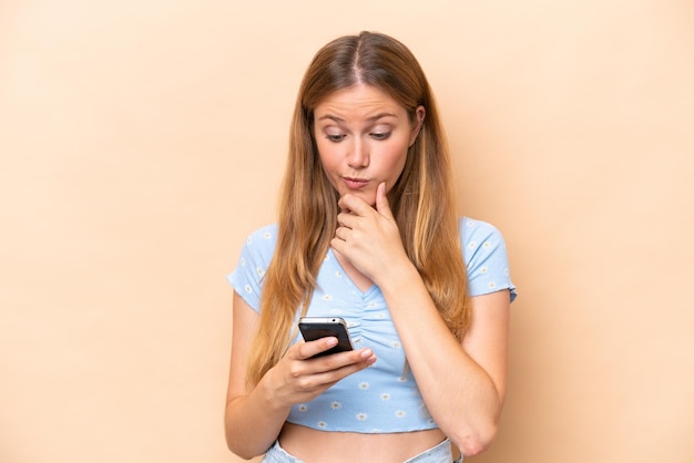 Young caucasian woman isolated on beige background thinking and sending a message