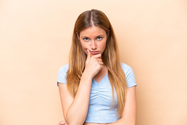 Giovane donna caucasica isolata sul pensiero beige del fondo