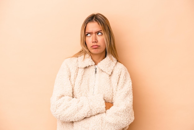 Young caucasian woman isolated on beige background tired of a repetitive task.