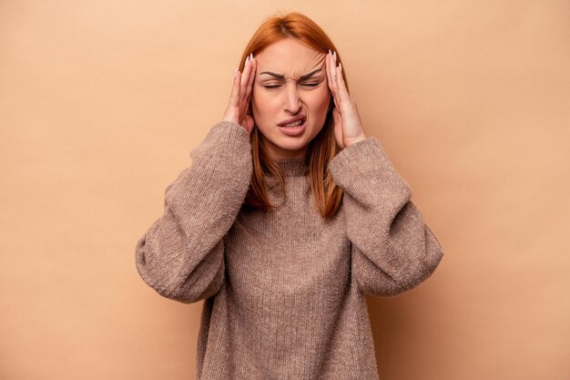 Young caucasian woman isolated on beige background touching temples and having headache