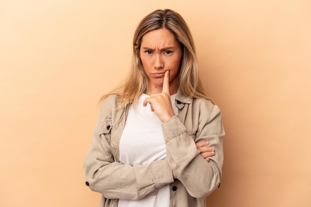 Young caucasian woman isolated on beige background unhappy looking in camera with sarcastic expression.