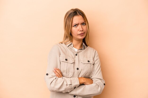 Photo young caucasian woman isolated on beige background unhappy looking in camera with sarcastic expression.