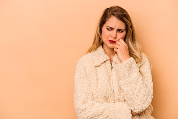 Young caucasian woman isolated on beige background who feels sad and pensive looking at copy space