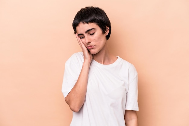 Young caucasian woman isolated on beige background who is bored, fatigued and need a relax day.