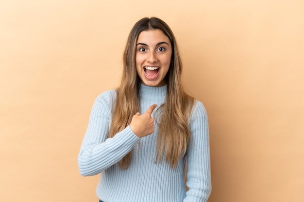 Young caucasian woman isolated on beige background with surprise facial expression