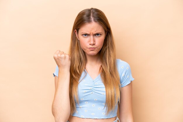 Young caucasian woman isolated on beige background with unhappy expression