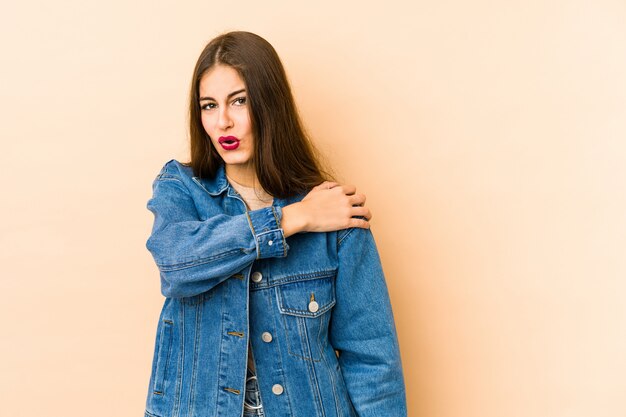 Young caucasian woman isolated on beige having a shoulder pain.