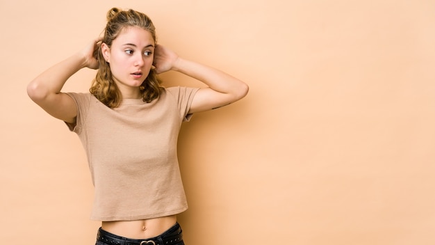 Foto giovane donna caucasica isolata su beige che grida, molto eccitata, appassionata, soddisfatta di qualcosa.