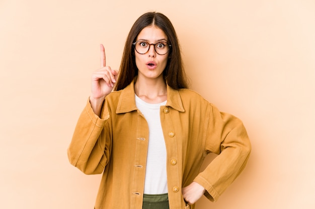 Young caucasian woman isolated on beige wall having an idea, inspiration concept.