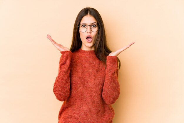 Young caucasian woman isolated on beige wall surprised and shocked.