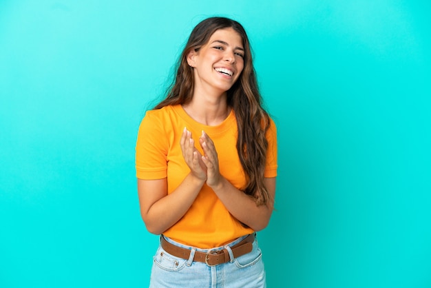 Young caucasian woman isolated on blue background applauding after presentation in a conference