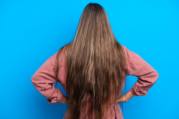 Young caucasian woman isolated on blue background in back position