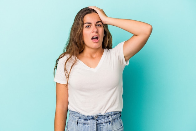 Young caucasian woman isolated on blue background  being shocked, she has remembered important meeting.