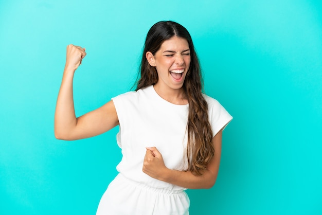 Young caucasian woman isolated on blue background celebrating a victory