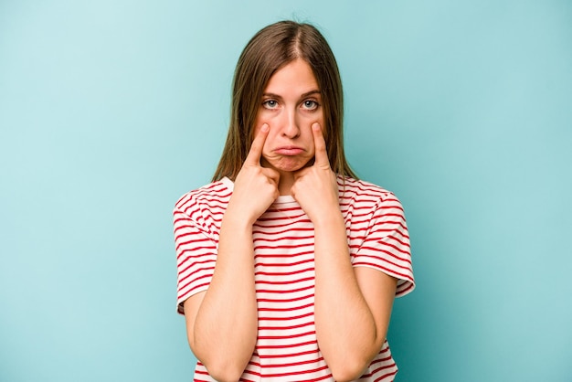 Young caucasian woman isolated on blue background crying unhappy with something agony and confusion concept