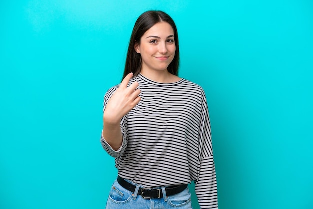 Young caucasian woman isolated on blue background doing coming gesture