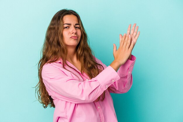 Young caucasian woman isolated on blue background  feeling energetic and comfortable, rubbing hands confident.