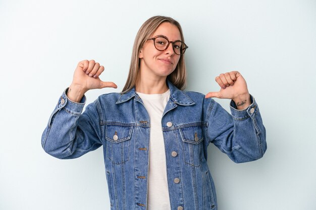 Young caucasian woman isolated on blue background feels proud and self confident, example to follow.