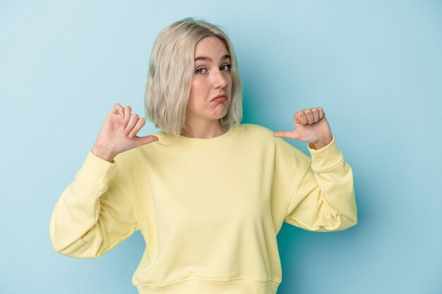 Young caucasian woman isolated on blue background feels proud and self confident, example to follow.