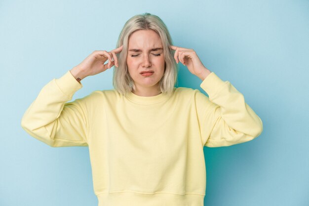 Young caucasian woman isolated on blue background focused on a task, keeping forefingers pointing head.