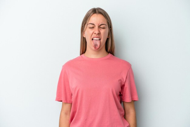 Young caucasian woman isolated on blue background funny and friendly sticking out tongue.