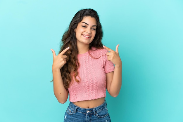 Young caucasian woman isolated on blue background giving a thumbs up gesture