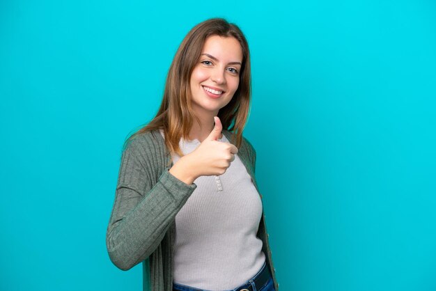 Young caucasian woman isolated on blue background giving a thumbs up gesture