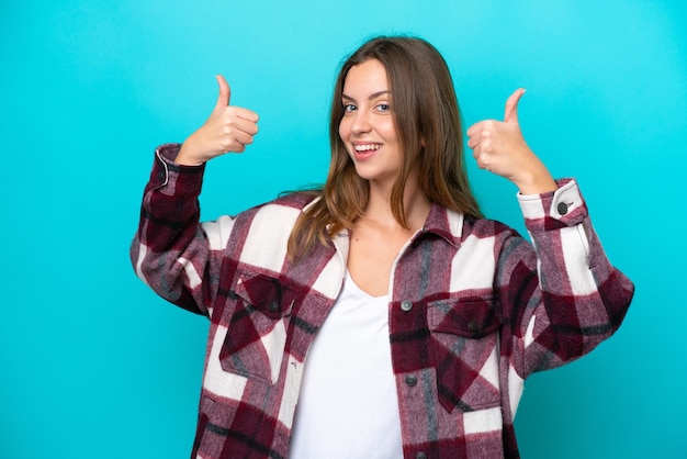 Young caucasian woman isolated on blue background giving a thumbs up gesture