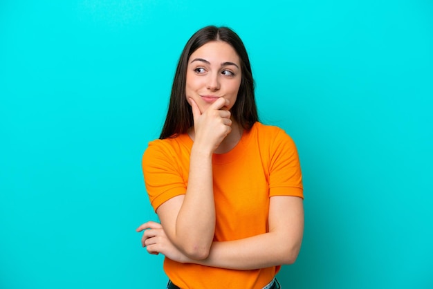 Young caucasian woman isolated on blue background having doubts and with confuse face expression