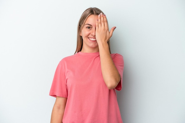 Young caucasian woman isolated on blue background having fun covering half of face with palm.