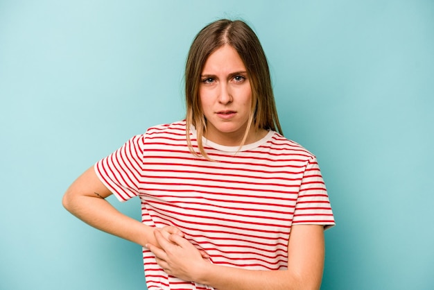 Young caucasian woman isolated on blue background having a liver pain stomach ache