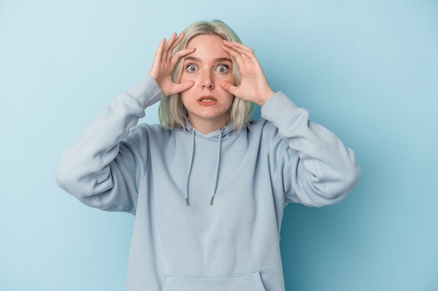 Young caucasian woman isolated on blue background keeping eyes opened to find a success opportunity.