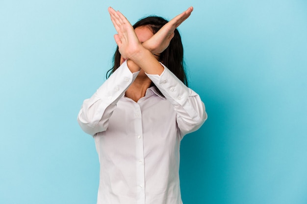 Young caucasian woman isolated on blue background keeping two arms crossed, denial concept.