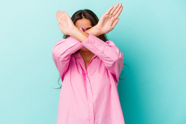 Young caucasian woman isolated on blue background  keeping two arms crossed, denial concept.