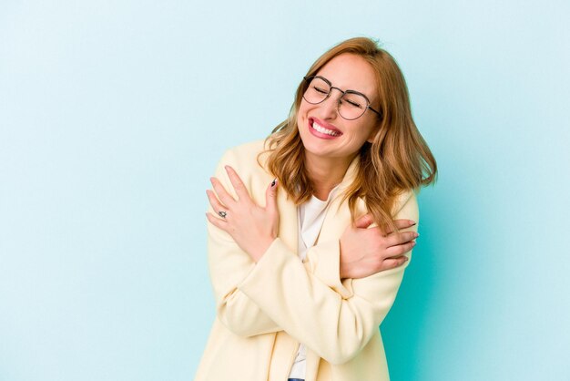 笑って楽しんで青い背景に孤立した若い白人女性。