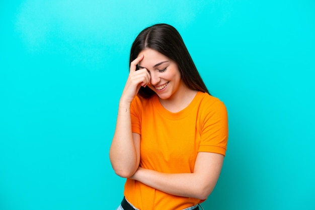 Young caucasian woman isolated on blue background laughing