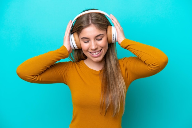 Young caucasian woman isolated on blue background listening music