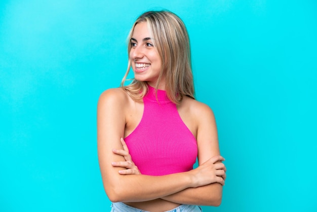 Young caucasian woman isolated on blue background looking to the side and smiling