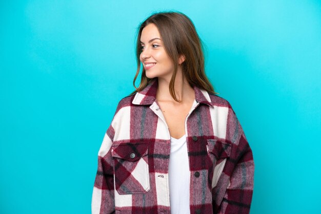 Young caucasian woman isolated on blue background looking side