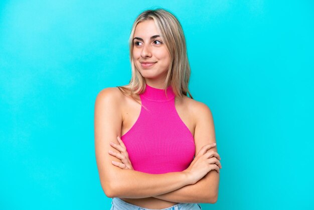 Young caucasian woman isolated on blue background looking to the side