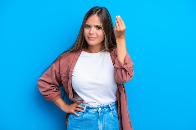 Young caucasian woman isolated on blue background making Italian gesture