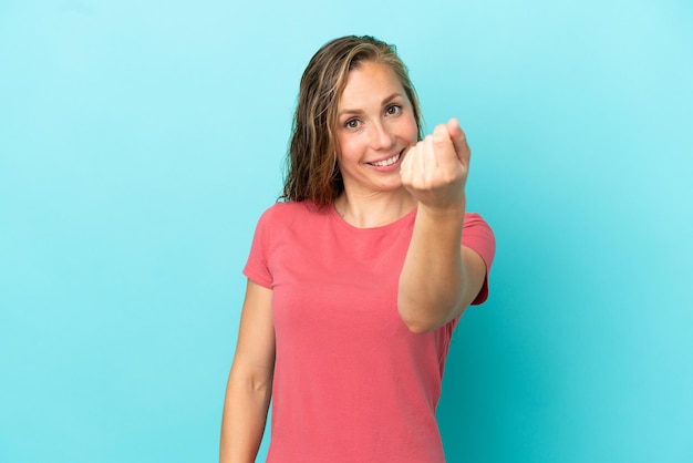 Young caucasian woman isolated on blue background making money gesture