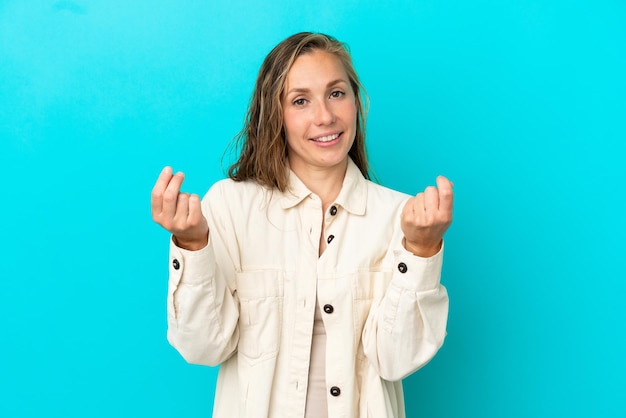 Young caucasian woman isolated on blue background making money gesture