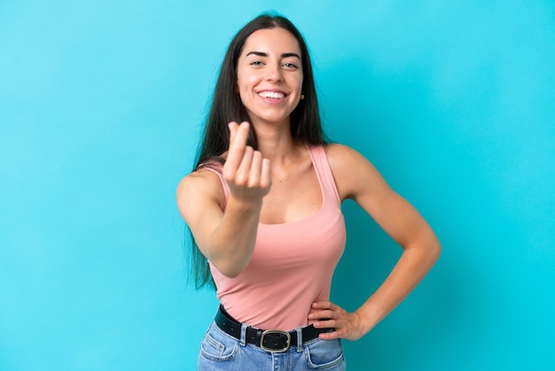 Young caucasian woman isolated on blue background making money gesture