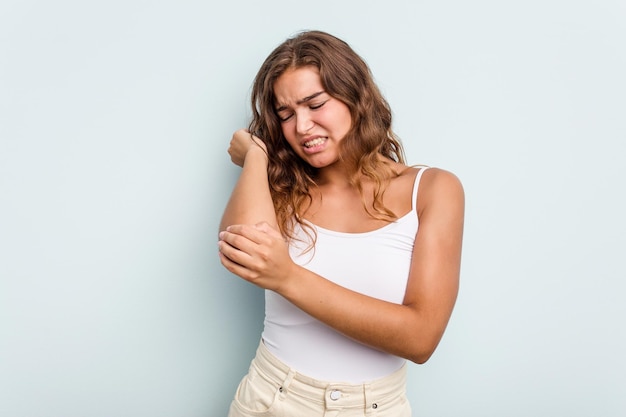 young caucasian woman isolated on blue background massaging elbow suffering after a bad movement