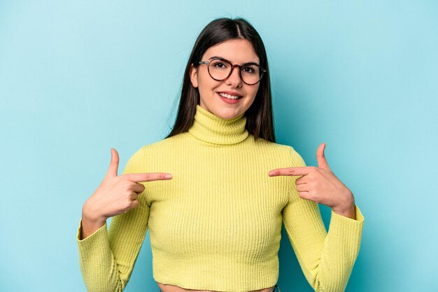 Foto giovane donna caucasica isolata su sfondo blu persona che punta a mano a uno spazio di copia camicia orgoglioso e fiducioso