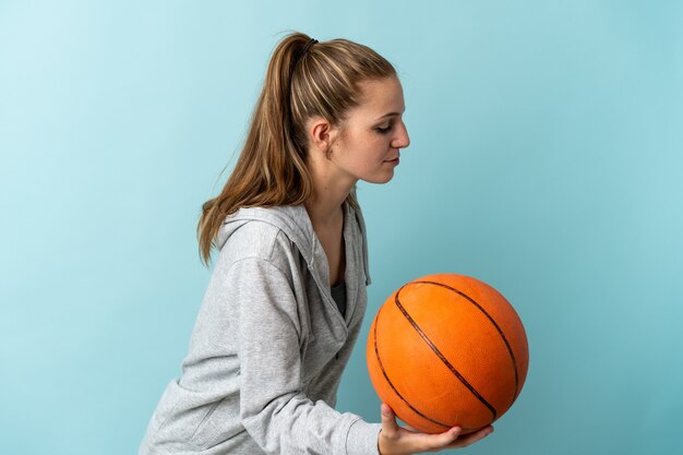 Young caucasian woman isolated on blue background playing basketball