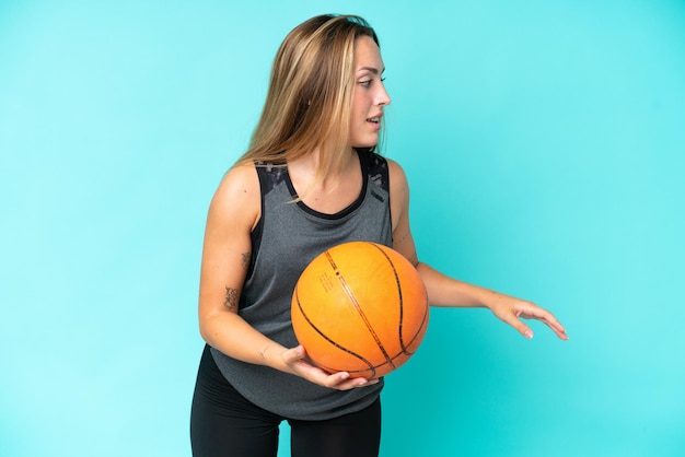 Young caucasian woman isolated on blue background playing basketball